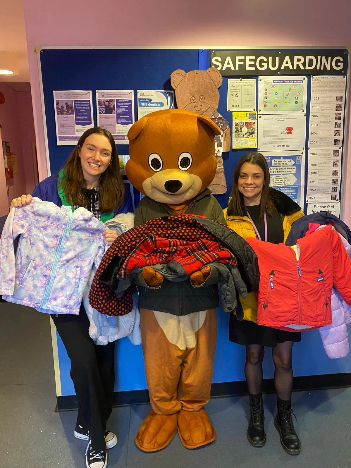 Clothing Donations with Bear Mascot Two Roberts Centre staff with a bear mascot holding donated children’s clothes