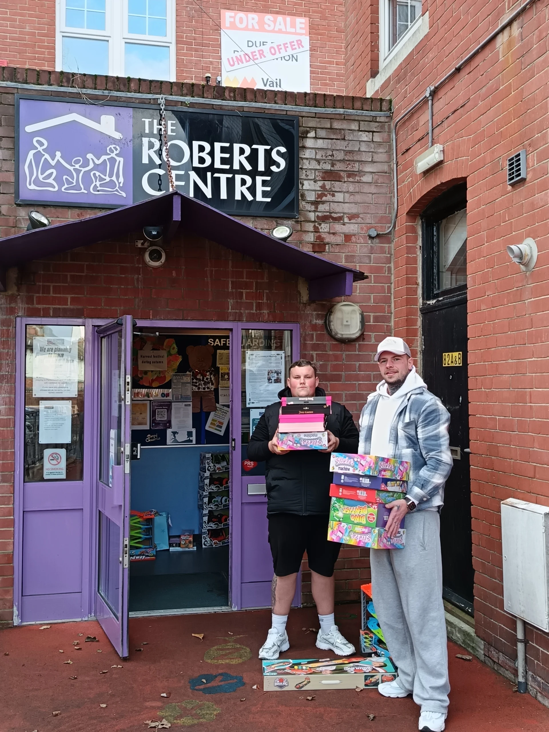 Gift Donations at the Roberts Centre Two men at the Roberts Centre entrance holding donated gift boxes